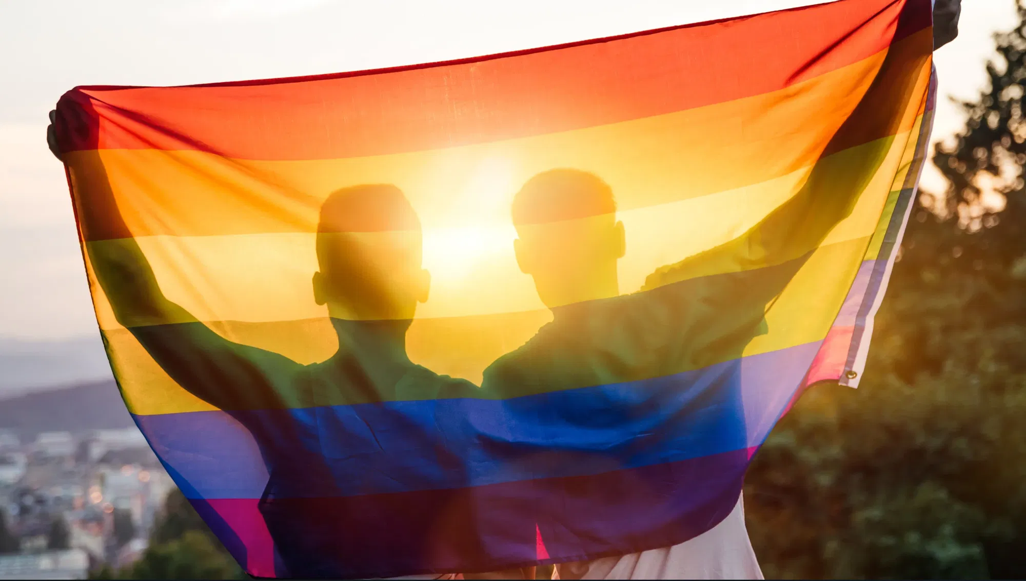 Silhouettes holding inclusivity flag high